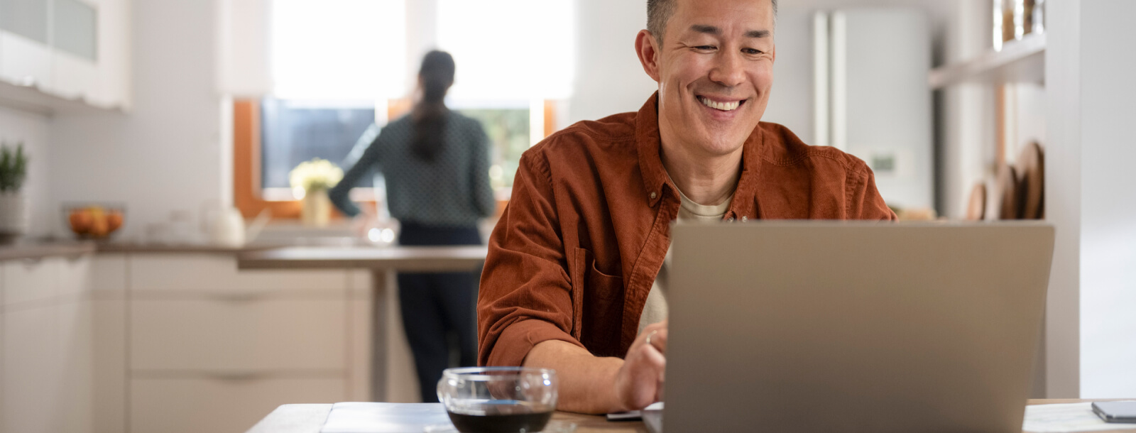man using laptop in his kitchen looking at Community National Bank's new website