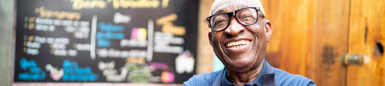 Man in apron smiling outside of his business